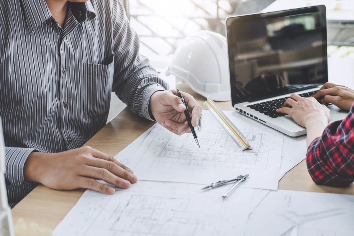  Deux professionnels collaborent sur des plans architecturaux à un bureau